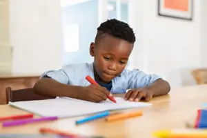 little boy paints in notebook at home