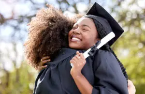 HIGHER EDUCATION PRODUCTS shot of a young woman hugging her friend on graduation day