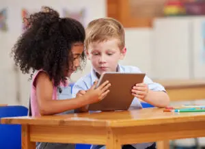 shot of two preschool students looking at something on a digital tablet together