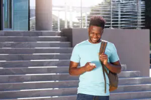 HIGHER EDUCATION PRODUCTS smiling african american student looking at cellphone